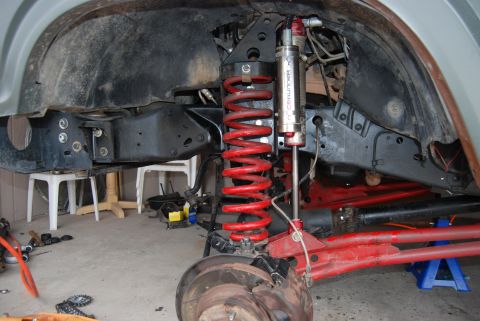 1982 Ford Bronco - Close-up view of a vehicle's modified suspension system with red springs and aftermarket shocks.