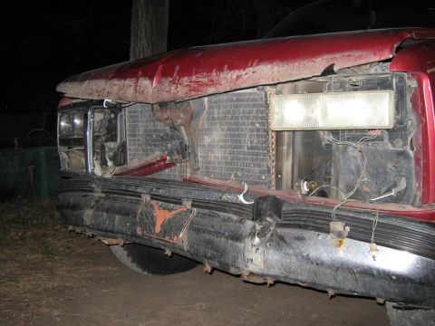 2000 Mercury Grand Marquis - Front end of a damaged red vehicle, showing the radiator and broken bumper.