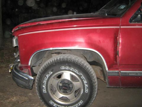 2000 Mercury Grand Marquis - A red GMC pickup truck's front section is visible, showing damage to the door and fender.