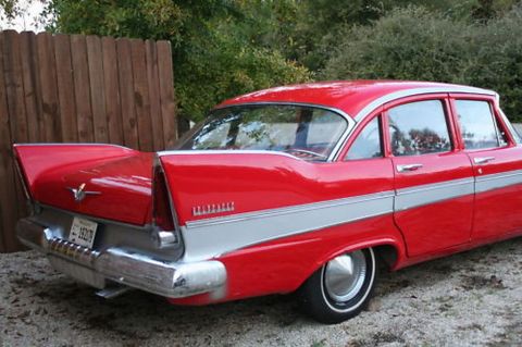 1991 Ford LTD Crown Victoria - Rear view of a classic red and silver sedan, identifiable by its distinctive tail fins and two-tone paint scheme.