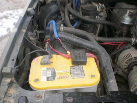 1995 Ford Bronco - Close-up view of an engine bay, highlighting a yellow Optima battery and the alternator.