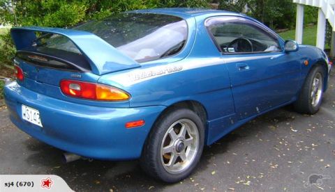 1993 Mazda MX-3 - Rear view of a blue 1993 Mazda MX-3 coupe, a prominent rear spoiler and side decal.