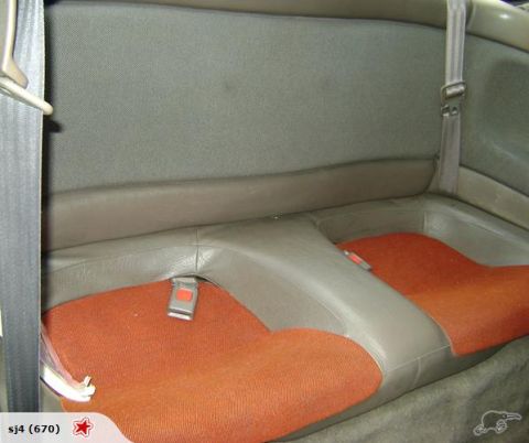 1993 Mazda MX-3 - Interior view of the rear seats of a car, orange fabric and grey trim.