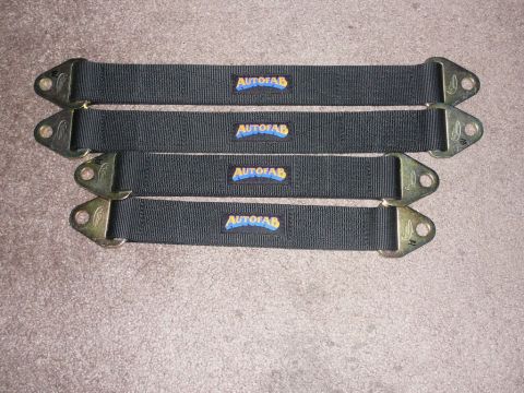 1988 Ford Bronco - Four black Autofab straps with metal mounting brackets are laid out on a carpeted surface.
