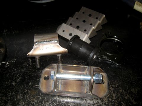 1996 Ford Bronco - Various metal brackets and a rubber bushing are laid out on a dark, textured surface.