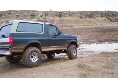 1995 Ford Bronco - This 1995 Ford Bronco, equipped with off-road tires, navigates a muddy, arid terrain.