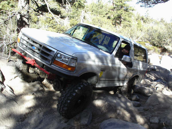 1996 Ford Bronco navigating a rocky trail with its front wheel lifted