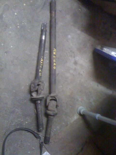 1968 Ford Mustang - Two driveshafts are laid out on a concrete floor, one with "FORD" written on it in yellow marker.