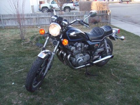 1980 Honda CB750 - A black 1980 Honda CB750 motorcycle is parked on a grassy area in front of a wooden fence.