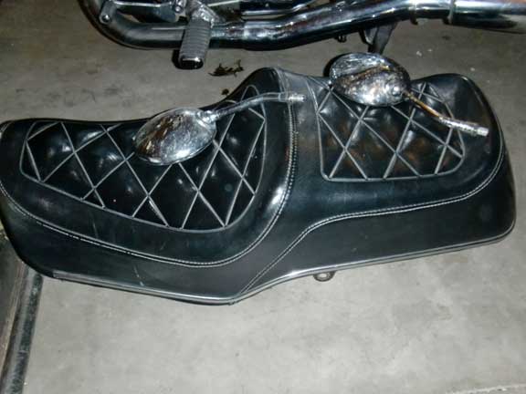 Black diamond-stitched motorcycle seat with two chrome mirrors resting on top