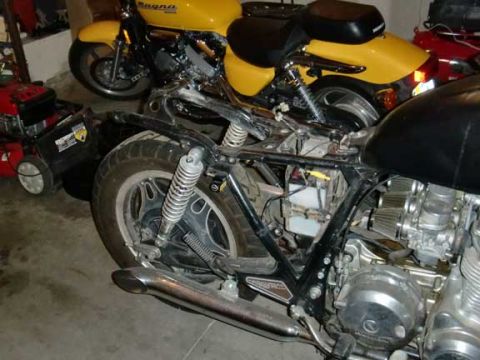 1980 Honda CB750 - A motorcycle's engine and frame are visible, alongside another motorcycle and a lawnmower in a garage setting.