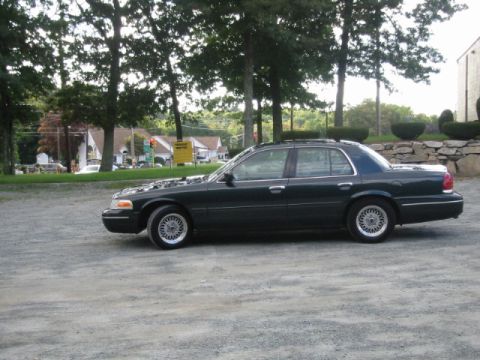 1998 Ford Crown Victoria - This dark 1998 Ford Crown Victoria is parked outside with its hood up.