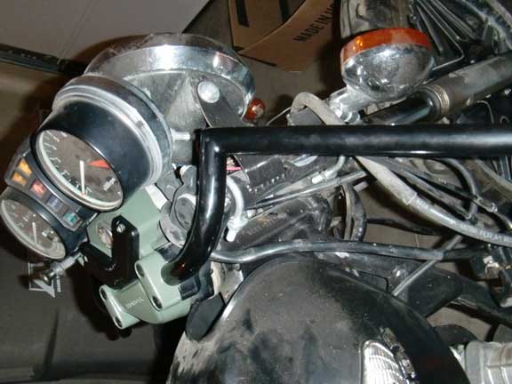 Motorcycle dashboard with two gauges, chrome headlight housing, and black handlebars