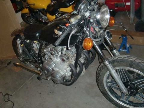 1980 Honda CB750 - Close-up of a 1980 Honda CB750 engine and front wheel assembly. Another motorcycle is visible in the background.