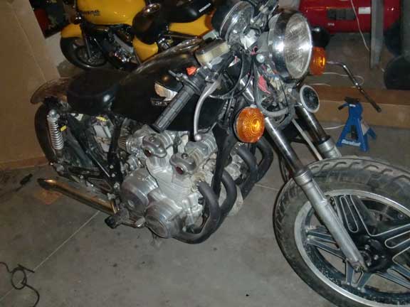 1980 Honda CB750 engine and front wheel, with a yellow motorcycle behind it
