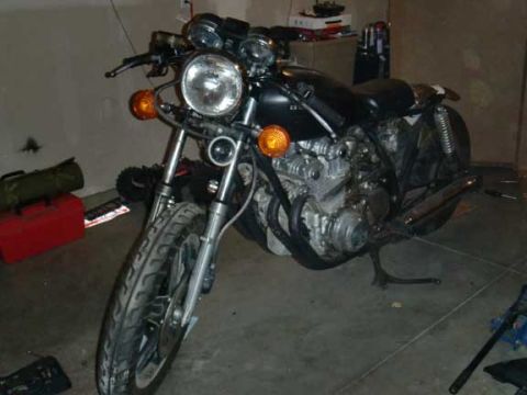1980 Honda CB750 - A motorcycle is parked indoors, possibly in a garage, with tools and storage items visible in the background.