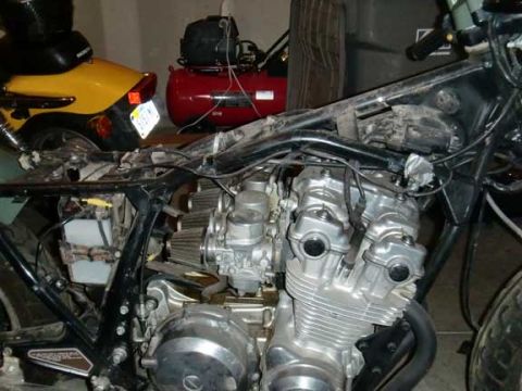 1980 Honda CB750 - Close-up of a motorcycle's engine and frame, with other vehicles and equipment visible.