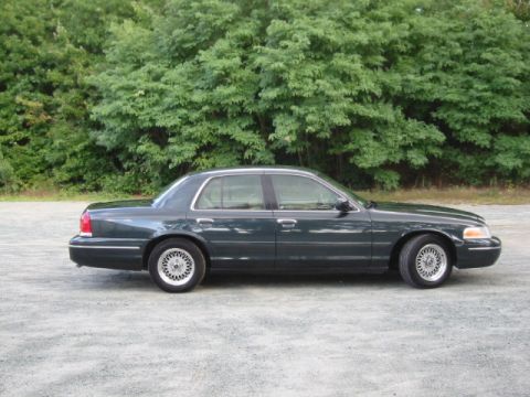 1998 Ford Crown Victoria - Side profile of a dark green 1998 Ford Crown Victoria sedan parked outdoors.