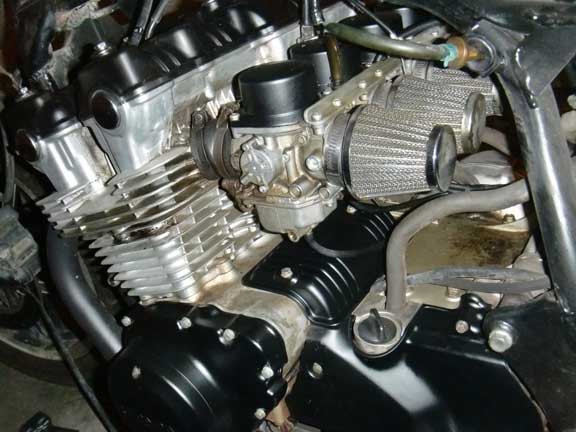 close-up of motorcycle engine, showing carburetors and aftermarket air filters