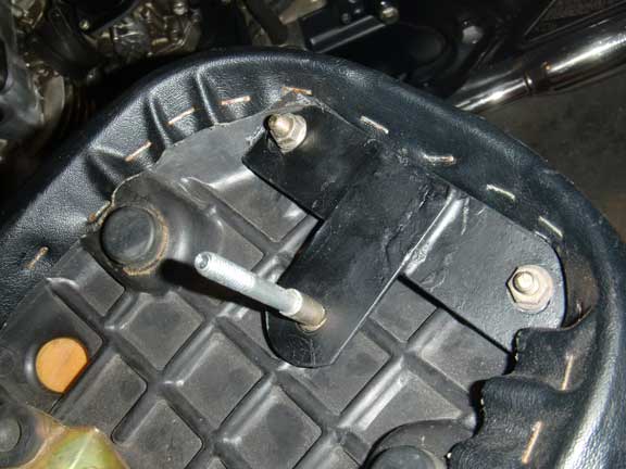 Close-up of a motorcycle seat's underside and mounting bracket