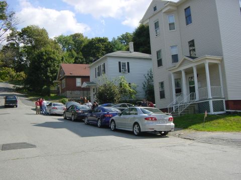 2003 Mazda 6 - A group of Mazda 6 sedans are parked on a street in front of houses.