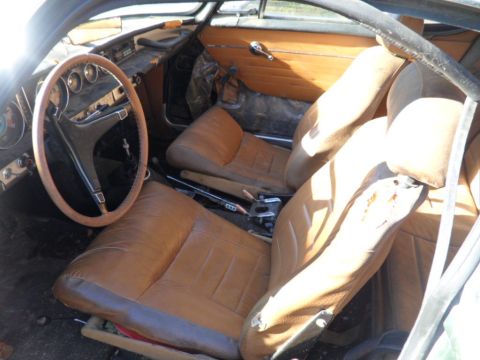1969 Volvo P1800 - The interior of a 1969 Volvo P1800 shows worn brown leather seats and wood trim.