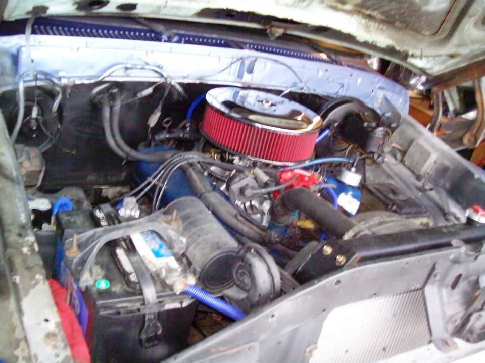Engine bay with red air filter, blue coolant reservoir, and battery