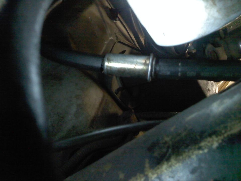 Black rubber hose joined by a metal splice fitting under a dirty vehicle chassis