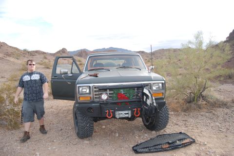 1982 Ford Bronco - Man stands next to a modified 1980s Ford Bronco in a desert setting with mountains in the background.