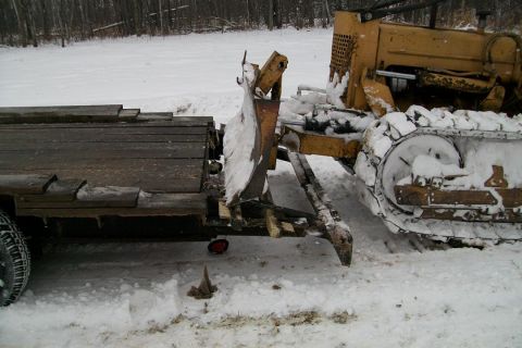 1963 Hummer H3 - A bulldozer is connected to a wooden trailer in a snowy environment.