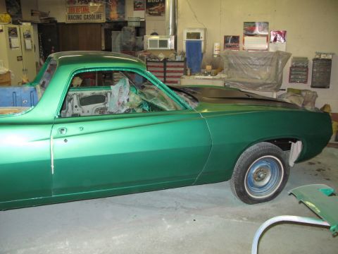 1971 Ford Ranchero - A 1971 Ford Ranchero in a shop, showing its side profile with fresh green paint and interior protection.