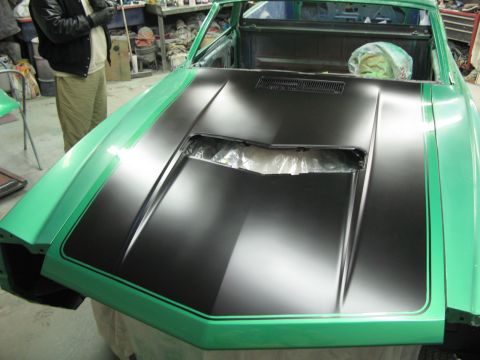 1971 Ford Ranchero - A car is being worked on in a garage, showing its hood and fender with a matte black stripe design.
