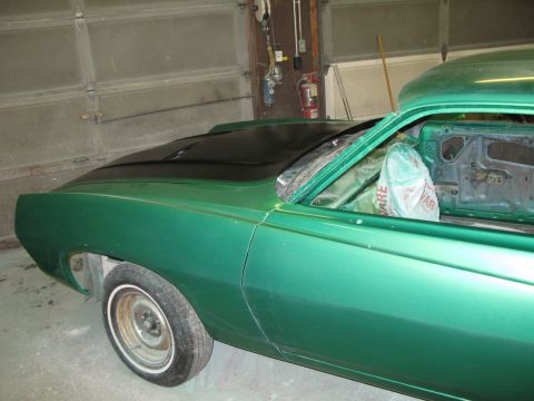 1971 Ford Ranchero - The side profile of a green 1971 Ford Ranchero shows its distinctive body style and a contrasting black hood.