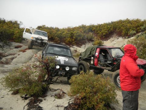 1997 Ford Ranger - Multiple off-road vehicles navigate a sandy and rocky terrain, with one vehicle in the foreground a Punisher skull decal.