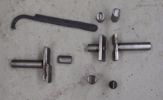 Metal parts and a curved tool laid out on a concrete surface