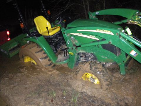 1989 Ford Bronco - A John Deere 4120 tractor is stuck in the mud at night.