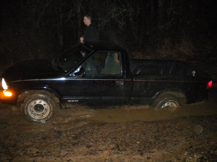 Black pickup truck stuck in mud, side view