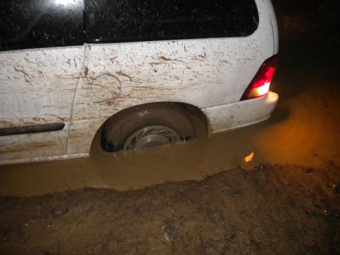 1989 Ford Bronco - Van stuck in mud, rear wheel deep in water and dirt.