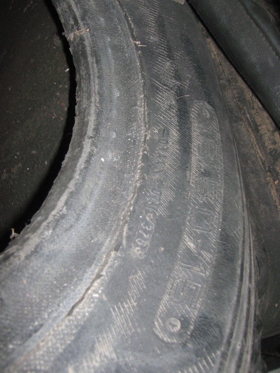 Close-up of a worn tire with visible tread markings and some text molded into the sidewall