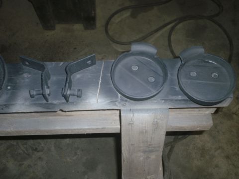 1995 Ford Bronco - Automotive parts, including brackets and circular components, are laid out on a wooden surface.