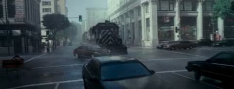 1993 Ford Taurus - A train moves through a city intersection during a rainstorm, with multiple cars present on the street.