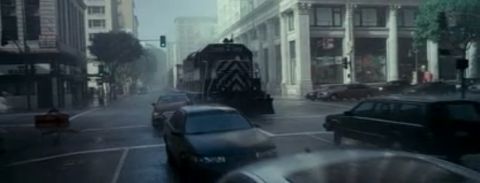 1993 Ford Taurus - A train passes through a city street with multiple cars, on a rainy day.