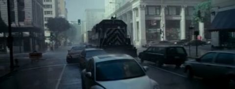 1993 Ford Taurus - A train travels down a city street lined with buildings and other vehicles.