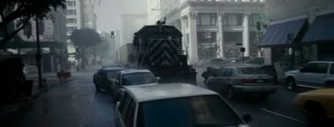 1993 Ford Taurus - A train moves through a city street lined with cars and buildings.