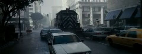1993 Ford Taurus - A train is stopped on a city street, causing a traffic jam with several cars waiting.