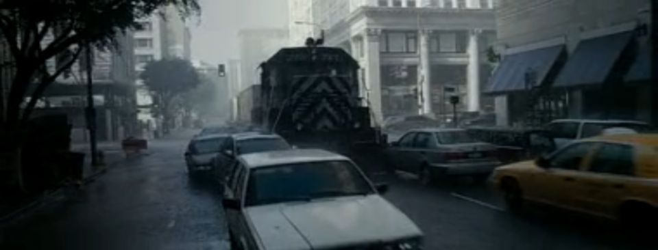 Train blocking traffic on a wet city street with cars lined up