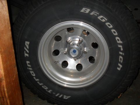 1990 Ford Bronco - Close-up of a BFGoodrich All-Terrain T/A tire with raised white lettering mounted on a polished aluminum eight-hole wheel with a five-lug p…