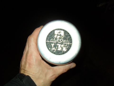1990 Ford Bronco - Flash photo at night of a hand holding a polished aluminum wheel center cap, showing the raised forged ALCOA stamping and additional letter…
