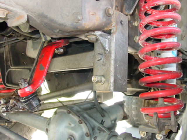 Underside view of front suspension with red coil spring and red suspension arm on a Ford Bronco