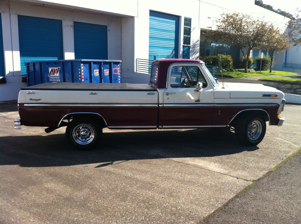 Side view of a maroon and white Ford pickup truck with a tonneau cover
